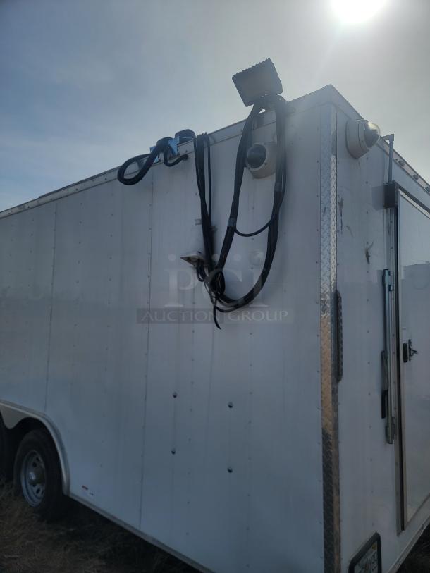 White mobile surveillance trailer with mounted cameras and cables, featuring floodlight and access door. Sturdy, good condition.