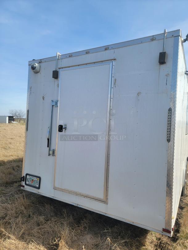 White enclosed trailer with security camera. Features rear door, visible door handle, and Florida license plate NZR Y89.
