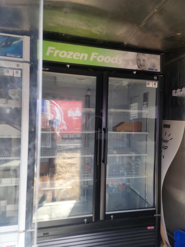 Glass door commercial freezer with "Frozen Foods" sign, Turbo Air branding, black frame, and visible shelving. Good condition.