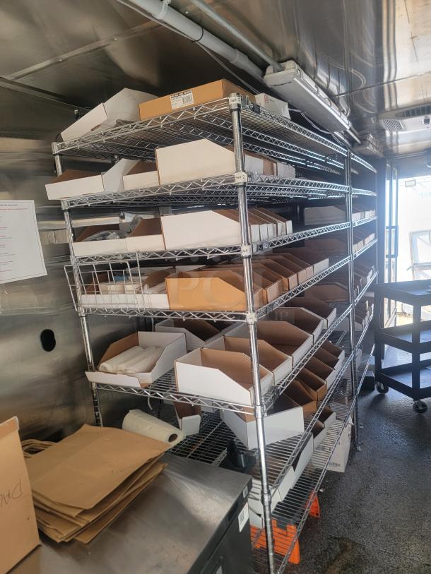 Metal shelving unit with multiple levels, holding various cardboard boxes and paper bags. Clean condition, ideal for storage.