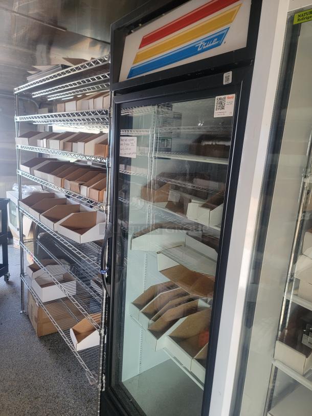 True commercial glass door refrigerator, display model, multi-colored logo, shelves inside, used condition.