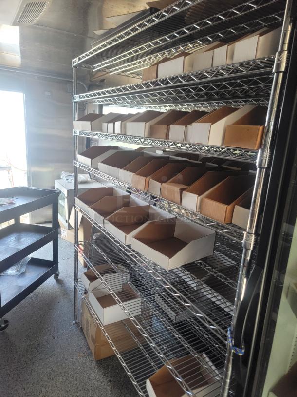 Stainless steel rolling rack with wire shelving and cardboard bins, in good condition. Suitable for storage or organization.