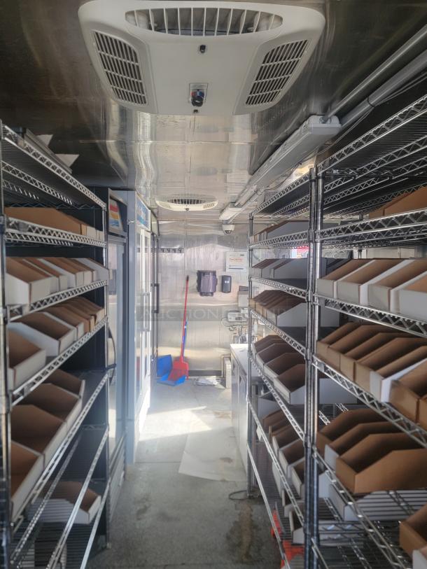 Stainless steel shelving unit with cardboard dividers in a well-maintained refrigerated storage area. Ceiling vent and cleaning supplies visible.