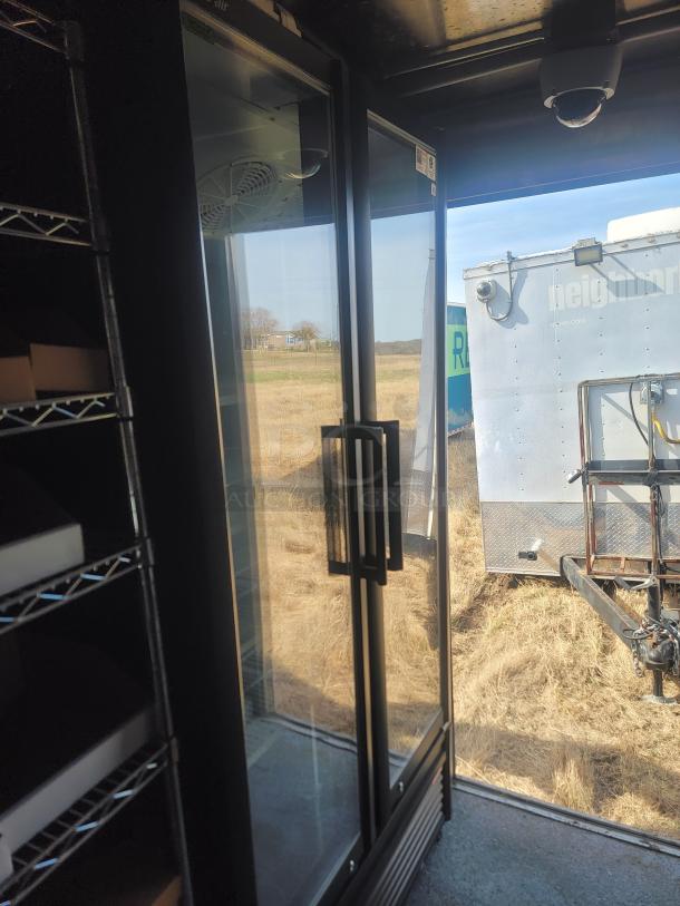 Double glass door commercial refrigerator with black frame, interior shelves, and exterior handles. In good condition.