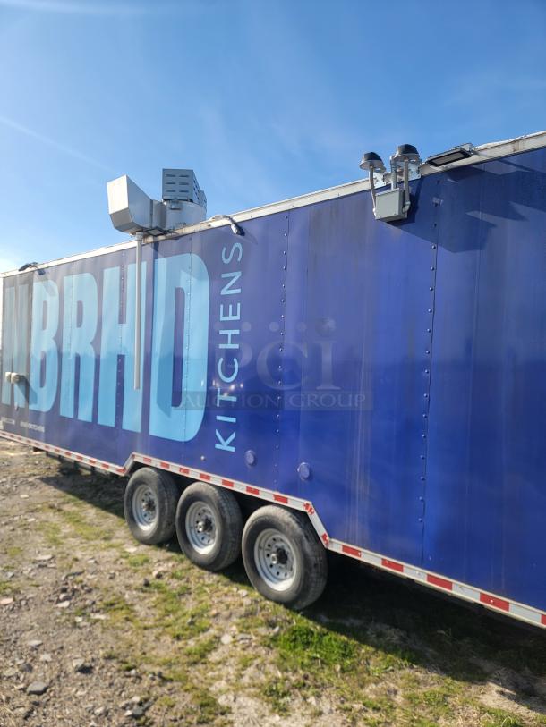 Blue mobile kitchen trailer with "BRHD Kitchens" branding, featuring rooftop ventilation units and six wheels.