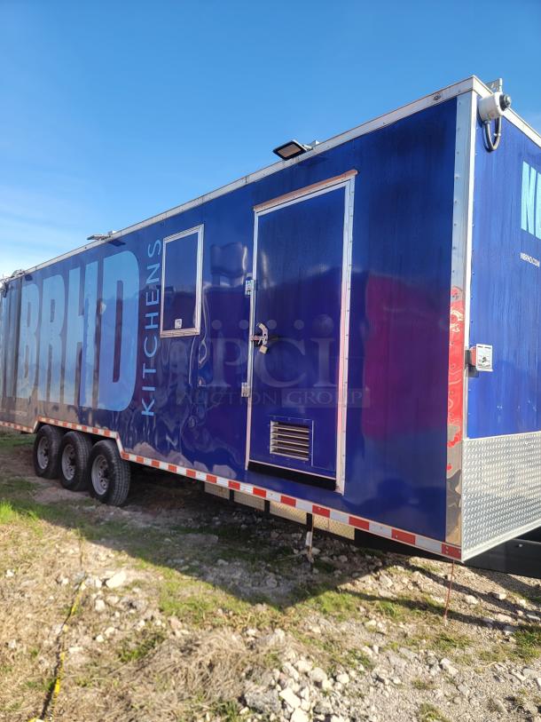 Mobile kitchen trailer in blue, featuring "BRHD Kitchens" branding. Triple-axle, with exterior access door and security lock. Good condition.