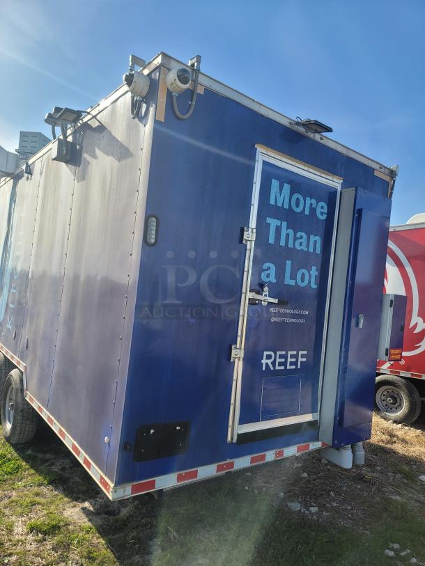 Blue mobile trailer by REEF, "More Than a Lot" slogan, security cameras, good condition, visible website URL.