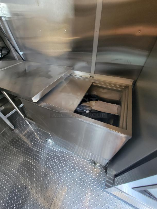 Stainless steel countertop with built-in storage compartment on wheels. Polished surface, industrial design, good condition.