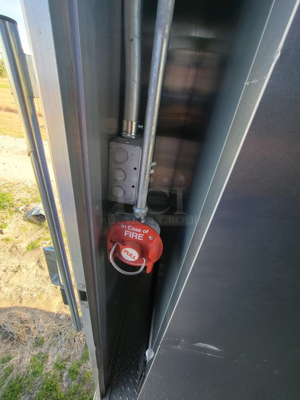 Red emergency fire pull station inside a metal panel with clear "In Case of FIRE" and "PULL" instructions.