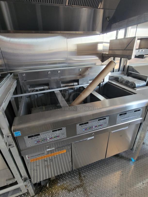 Commercial deep fryer by Frymaster, stainless steel, four electronic panels, industrial condition, visible grease stains.