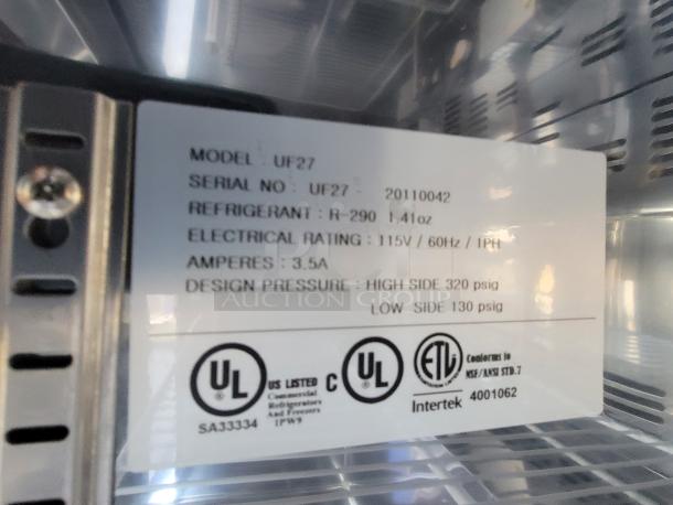 Metallic appliance interior with a model label indicating: Model UF27, serial 20110042, refrigerant R-290, electrical rating 115V/60Hz/1PH, 3.5A, design pressure 320 psig high side, 130 psig low side. UL and Intertek certified.