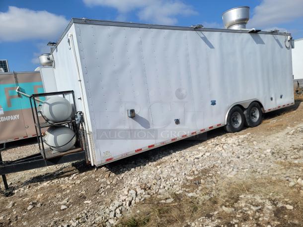 Mobile kitchen trailer with twin axle, vent hoods, and propane tanks. White exterior, suitable for food service operations.