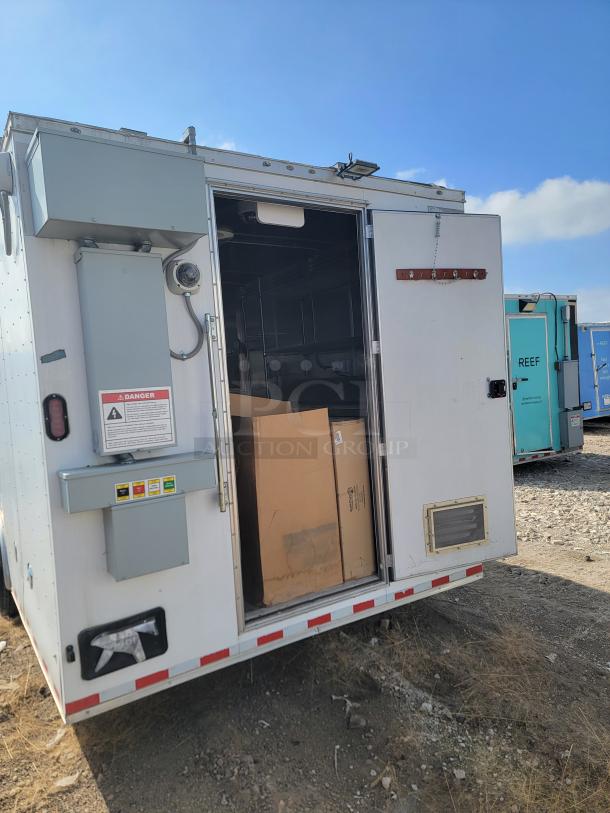Mobile storage unit with an open door, revealing cardboard boxes inside. Exterior includes caution labels and metal paneling.