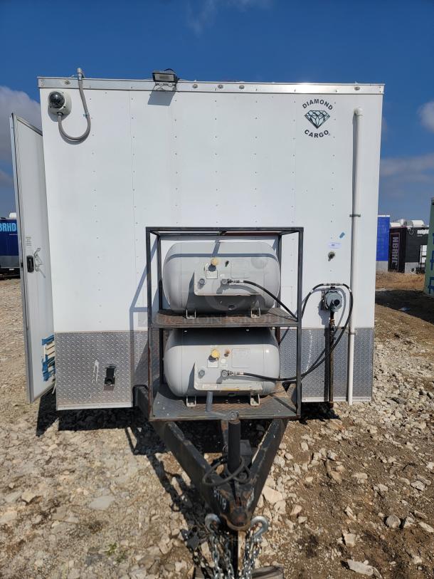 Diamond Cargo trailer with dual propane tanks, hitch, and utility features. White exterior with logo. Good condition.