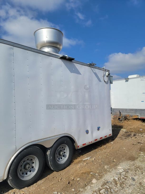 White utility trailer with dual axles and roof vent. Appears in good condition. No visible markings or labels.