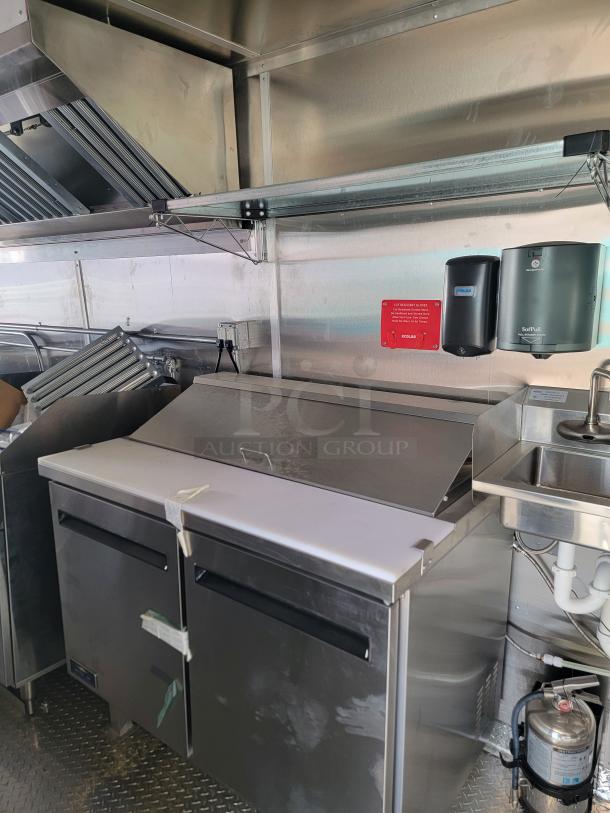 Commercial stainless steel refrigerated prep table with dual doors and cutting surface. Ideal for restaurant kitchens.