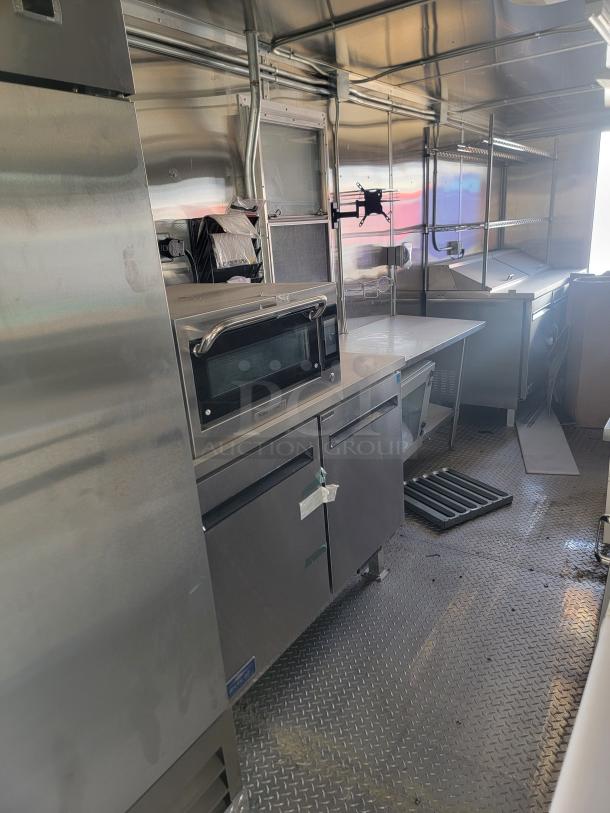 Commercial-grade stainless steel kitchen interior with oven, shelving, and counter space. Clean and well-maintained condition.