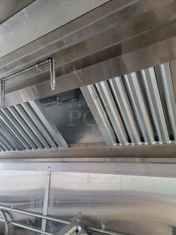 Stainless steel commercial kitchen hood vent with baffle filters and fire suppression nozzles, excellent condition.