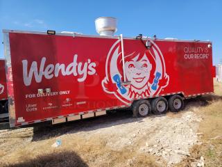 Red Wendy's food trailer with branding and delivery service logos, three axles, vent on top, parked on grass.