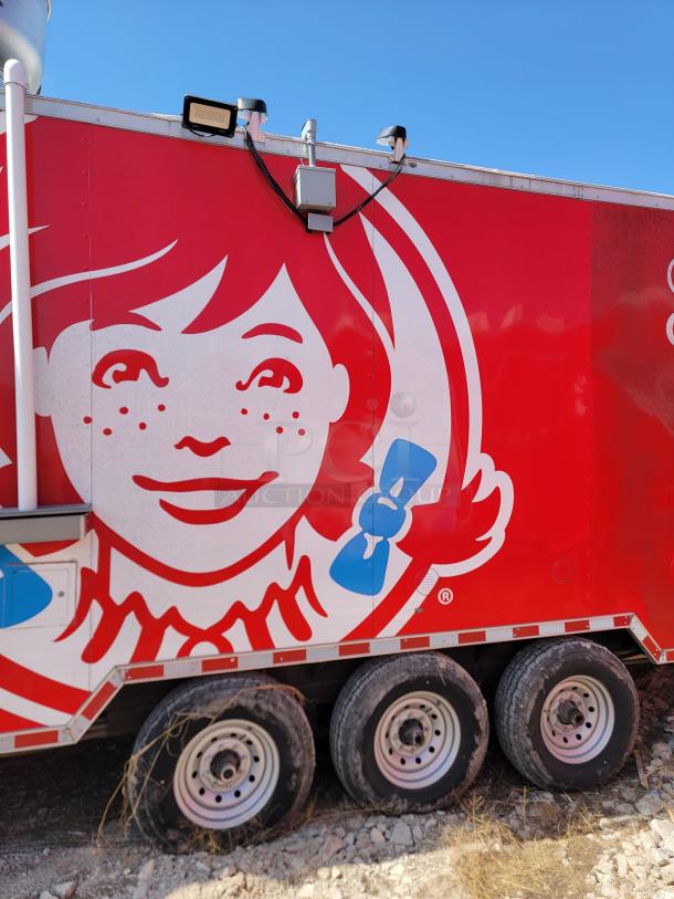 Red food truck with Wendy's logo, featuring triple axle wheels. Condition appears used, ideal for mobile food business.