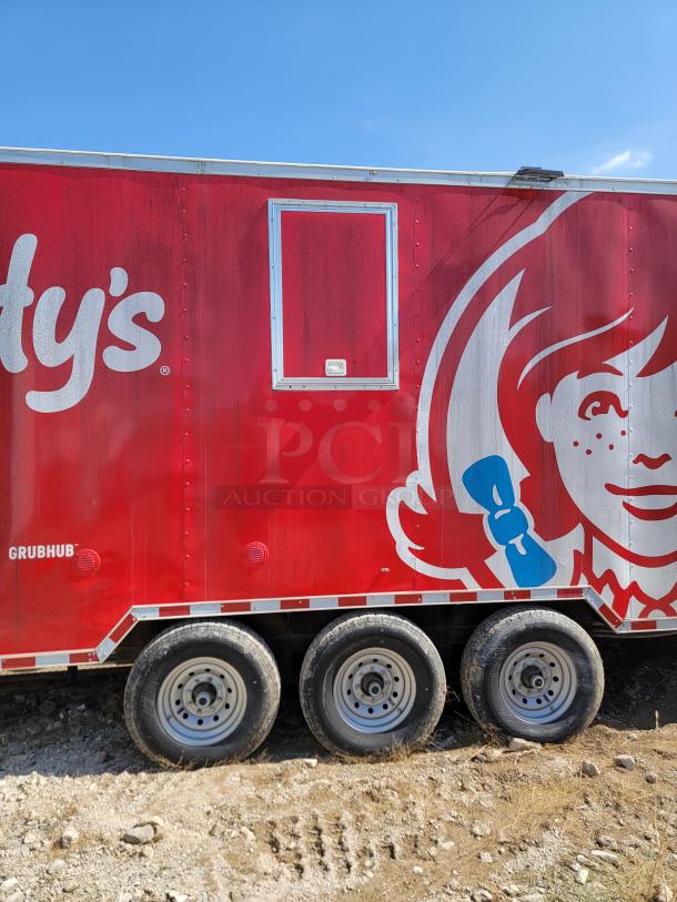Red Wendy's food truck trailer with tri-axle wheels, exterior signage featuring logo, and service window on the side.