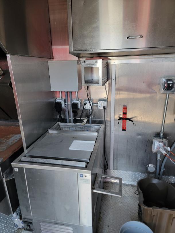 Commercial refrigeration unit in industrial kitchen setting, stainless steel body, visible electric outlets, good condition.