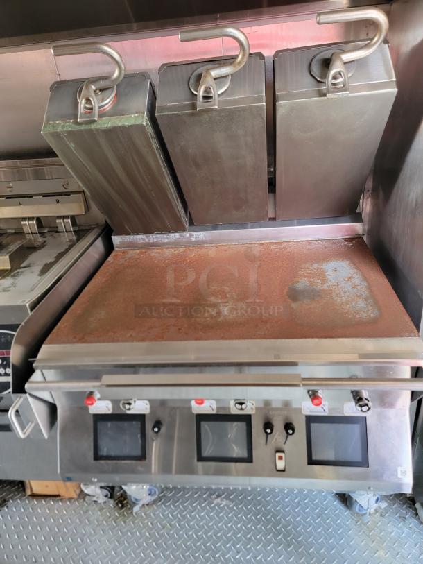 Commercial griddle with three clamshell lids, showing signs of rust. Features control panel with touch screens.