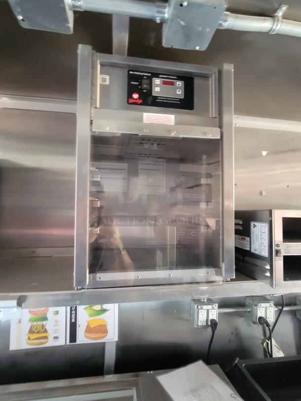 Commercial stainless steel warming cabinet with digital controls, visible brand label, and interior shelving, used condition.