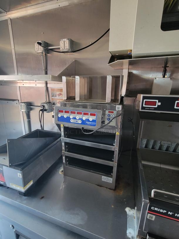 Commercial kitchen warmer with multiple shelves, digital controls, and stainless steel design. Used condition. Electrical setup visible.