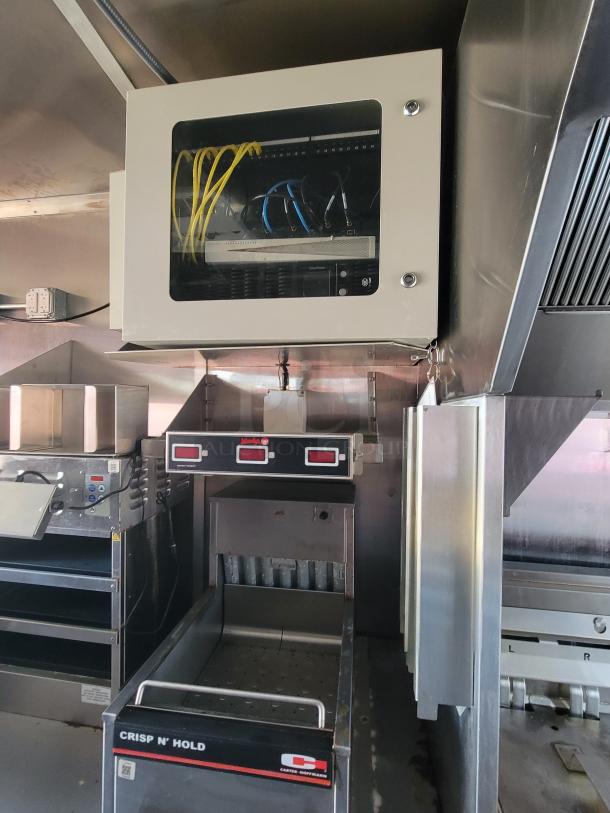 Commercial kitchen equipment with a wall-mounted network cabinet. Includes a Carter-Hoffmann Crisp N’ Hold model. Appears in used condition.