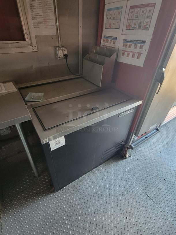 Commercial stainless steel ice cream freezer with top lid, model identifiable by visible QR code. Used condition.