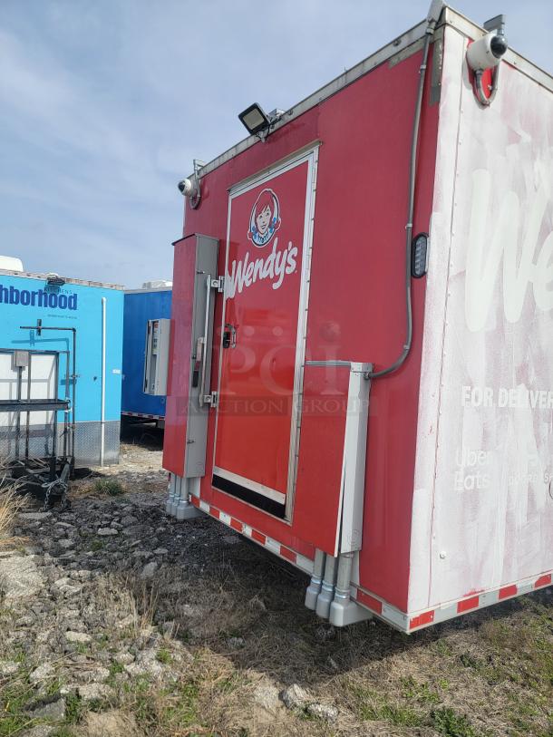 Red Wendy's food truck with logo, visible wear, and delivery service decals. Equipped with surveillance cameras. Ideal for mobile vending.