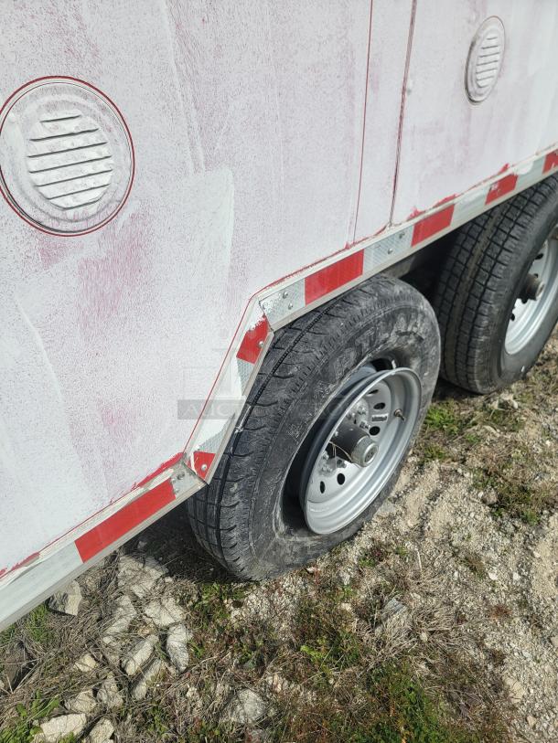 Red and white utility trailer with dual wheels, weathered finish, and visible tire wear. Vent covers on the side.
