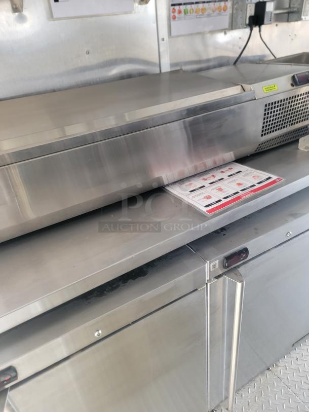 Commercial stainless steel food prep station with refrigeration, visible temperature control, and storage compartments, in used condition.