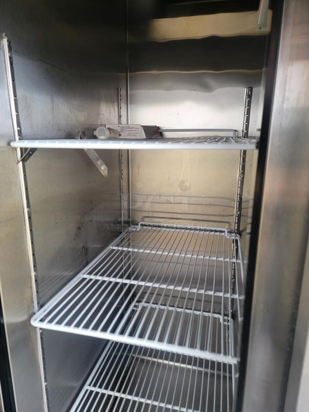Stainless steel refrigerator interior with three wire shelves, silver finish, some visible wear.
