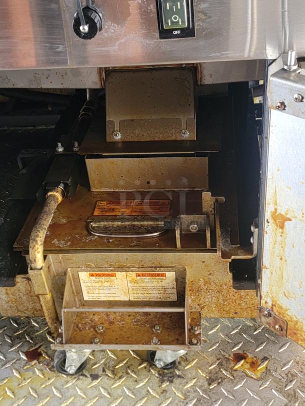 Commercial metal appliance with power switch, showing signs of rust. Includes visible warning labels on surface. Condition: used.