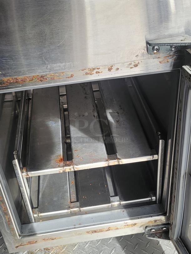 Stainless steel commercial oven with visible rust and wear, featuring metal racks and an open door. Suitable for restoration.