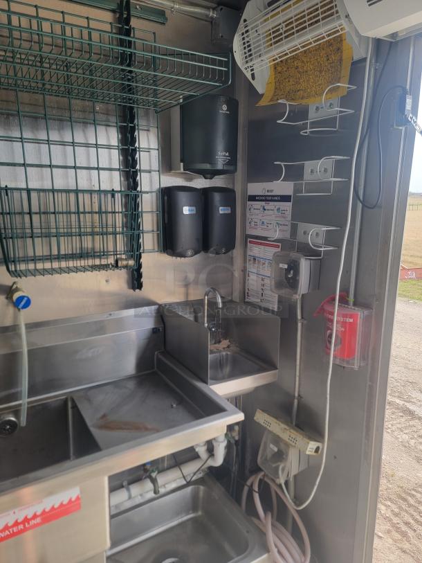Industrial kitchen setup with stainless steel sinks, soap dispensers, wire shelving, and hygiene instructions. Good condition.