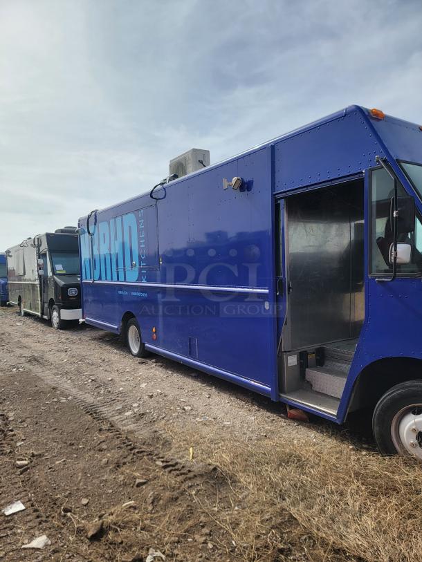 Blue food truck labeled "Hybrid Kitchens," clean exterior, side entrance open, rooftop air unit. Appears in good condition.