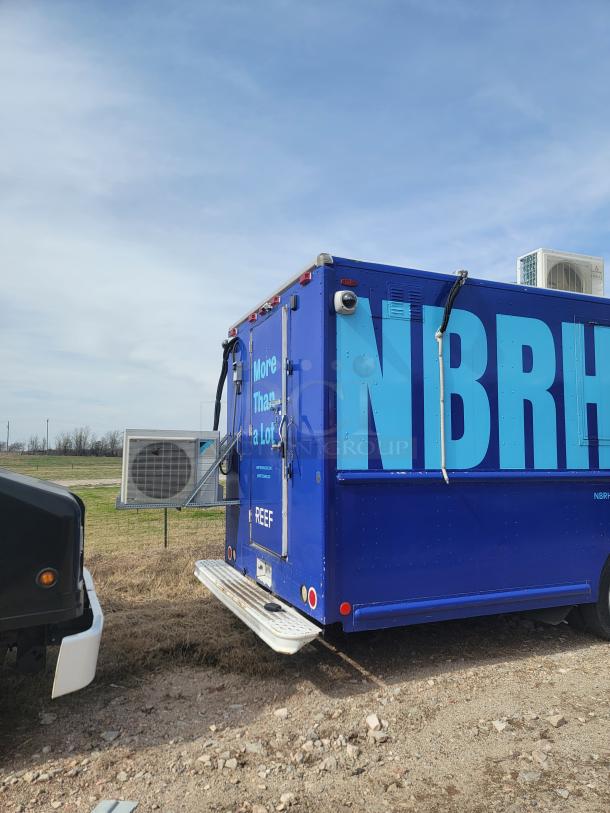 Blue mobile unit with "NBRH" text, rear access door, and REEF branding. Exterior air conditioning unit visible.