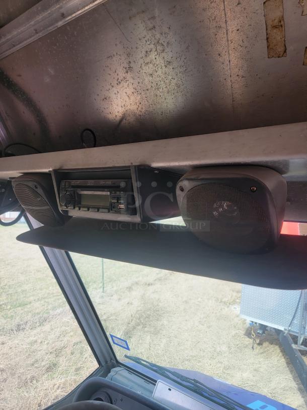 Vehicle interior roof with installed radio and speakers, showing worn metal and wiring. Condition appears used.