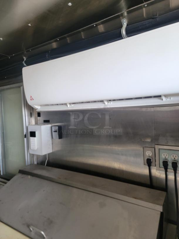 White industrial HVAC unit mounted on stainless steel interior wall, featuring a digital control panel; appears in good condition.