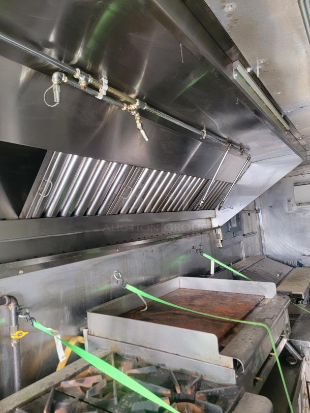 Commercial kitchen setup with stainless steel vent hood and cooking equipment, including grill and burners. Used condition.