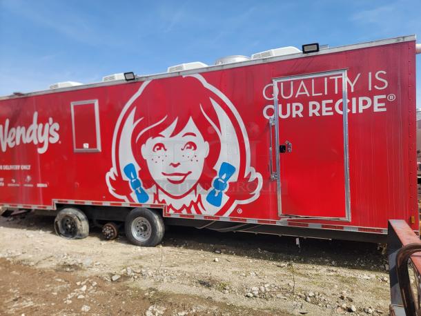 Red Wendy's mobile kitchen trailer with large logo and slogan "Quality is Our Recipe." Missing one wheel, used condition.