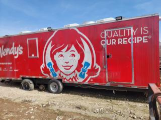 Red Wendy's mobile kitchen trailer with large logo and slogan "Quality is Our Recipe." Missing one wheel, used condition.