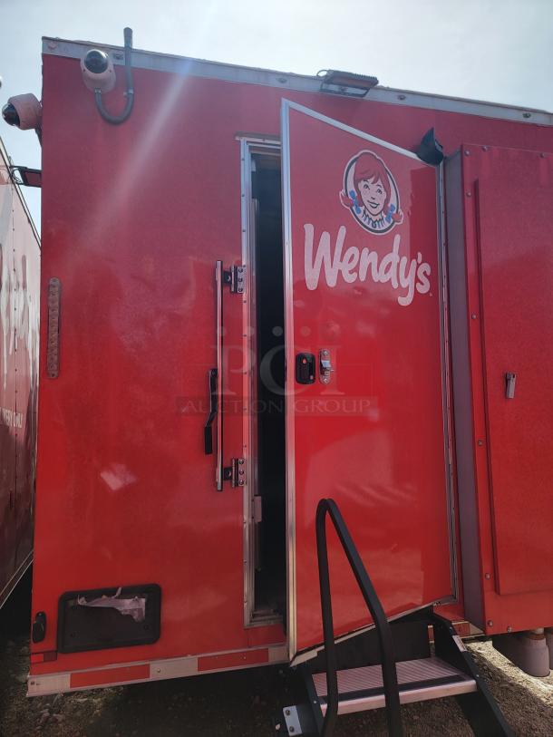 Red mobile trailer with Wendy's logo, partially open door, installed security cameras. Good condition, exterior step access.