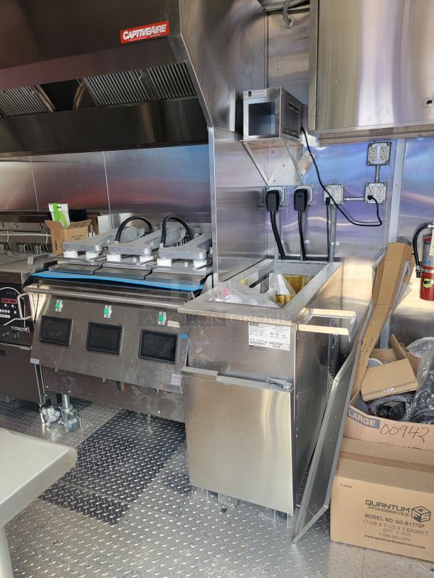 Commercial kitchen setup with CaptiveAire ventilation, three waffle makers, and Quantum foodservice fryer. New condition.