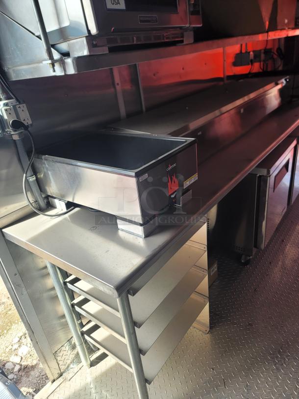 Stainless steel commercial kitchen setup with multiple shelves and a countertop appliance, featuring a "cayenne" brand label.
