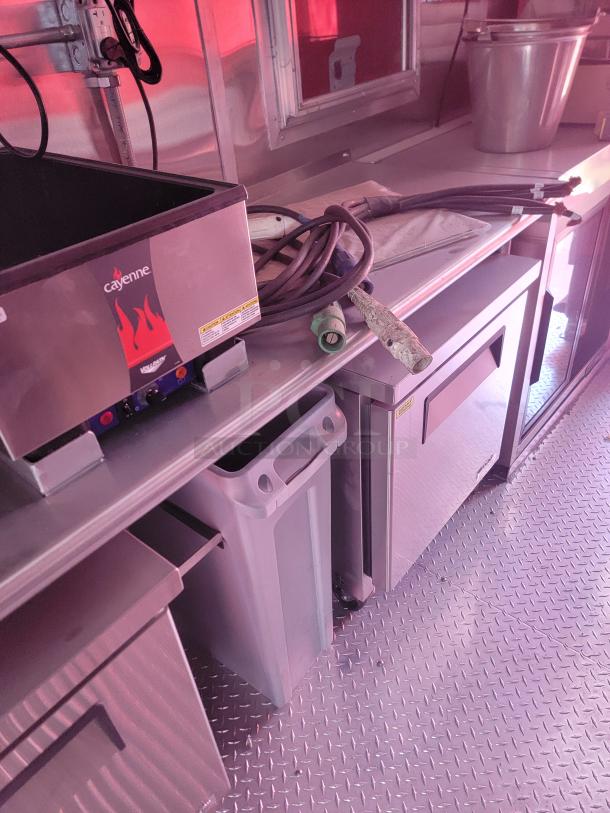 Commercial kitchen equipment featuring a Cayenne deep fryer, stainless steel counter, and storage units in good condition.