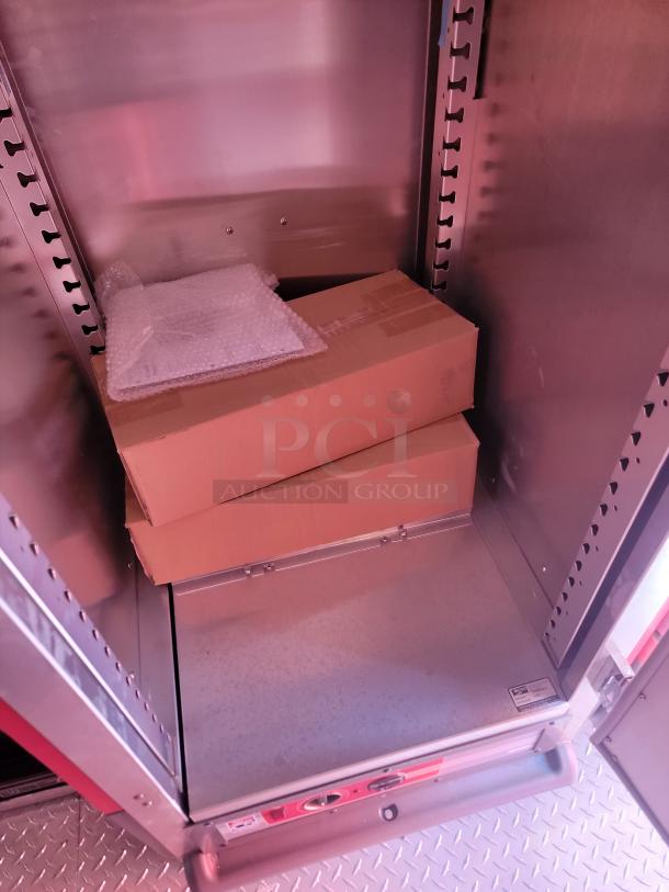 Metal storage compartment with cardboard boxes and bubble wrap. Shelving slots on sides. Clean and sturdy condition.